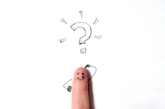 クエスチョンマークの下で考える顔が描かれた指