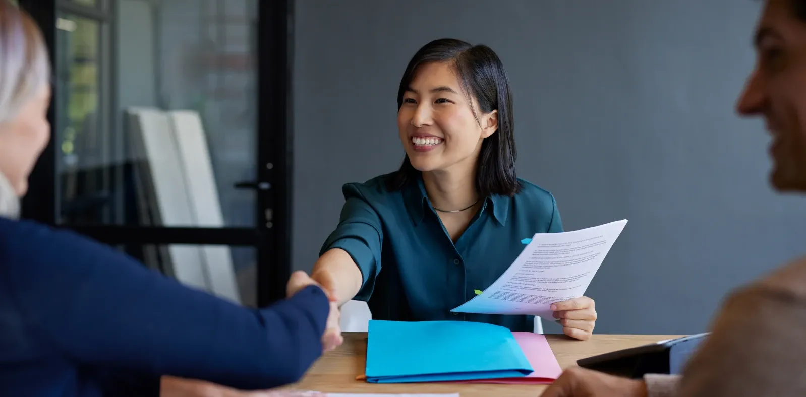 A candidate shaking hands with two interviewers at the end of an interview