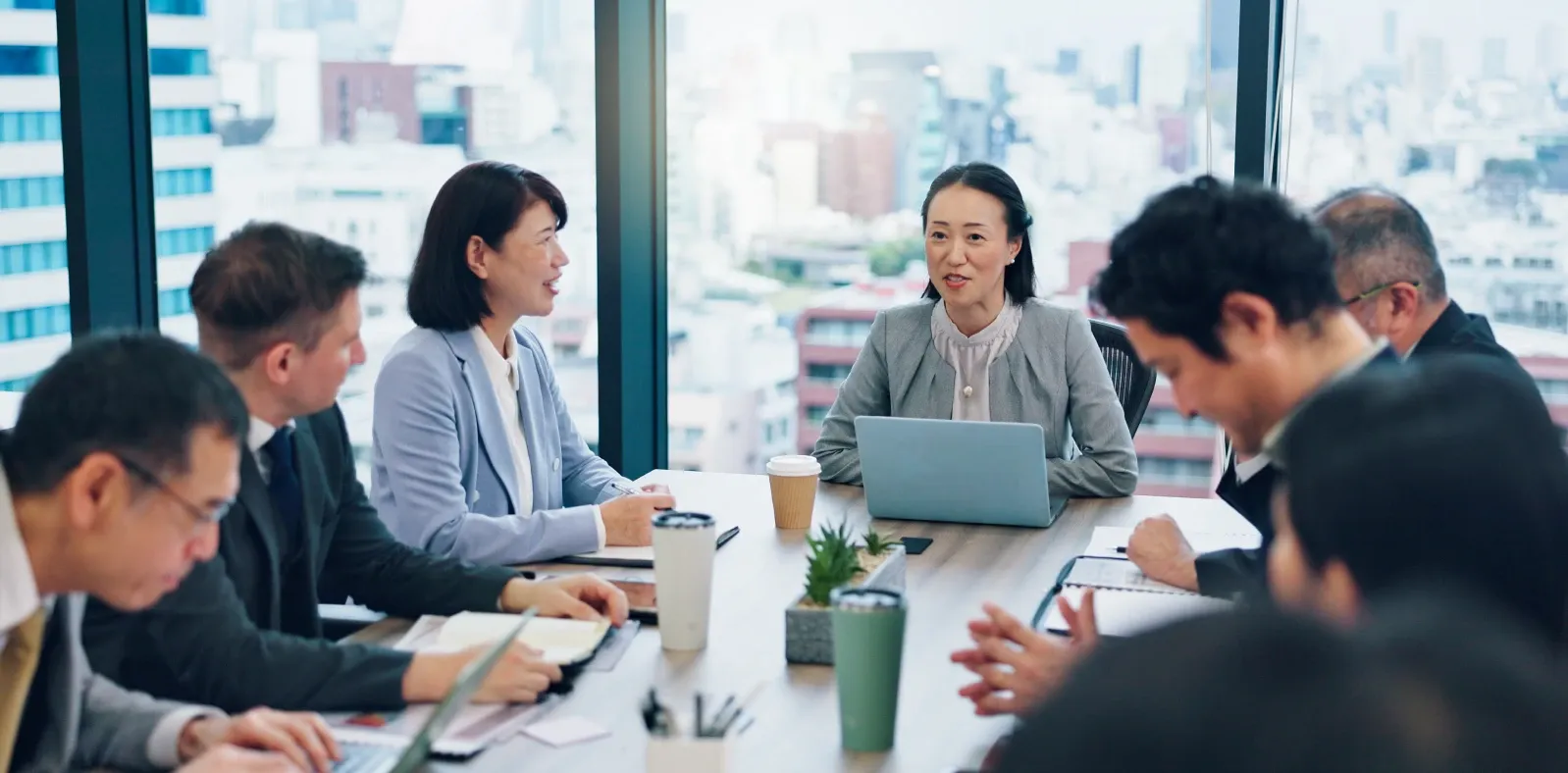 Colleagues around a boardroom table listening to a speaker