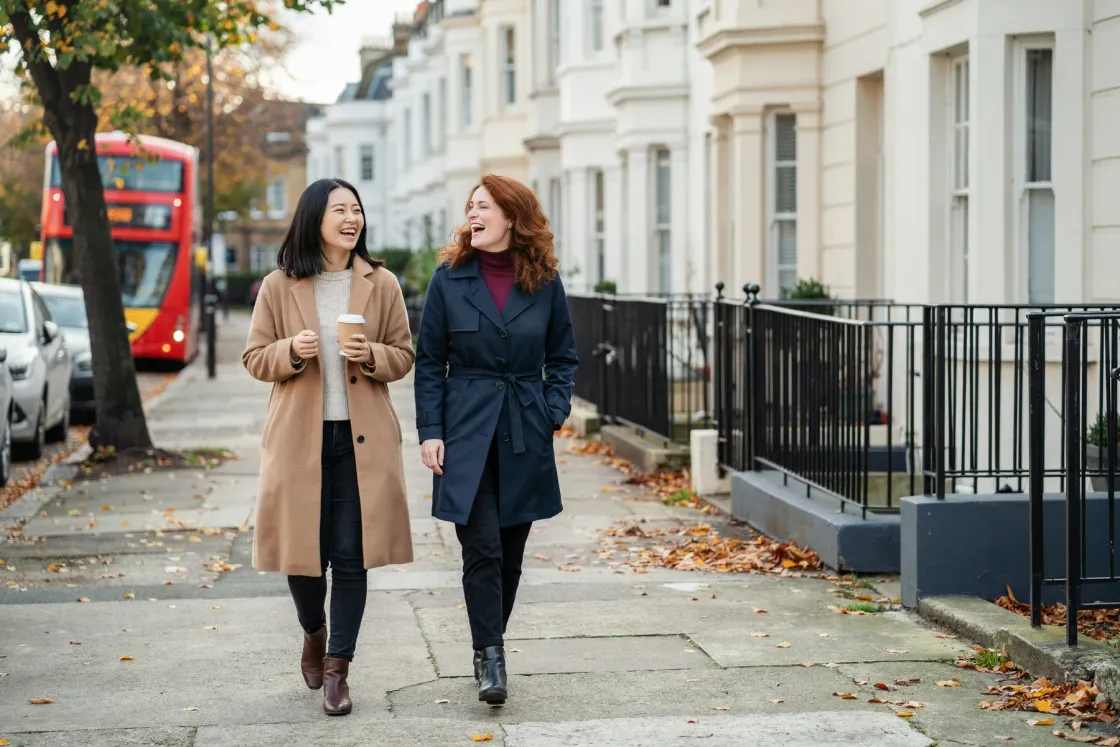 秋のロンドンの住宅街を、笑いながら並んで歩く日本人女性とイギリス人講師