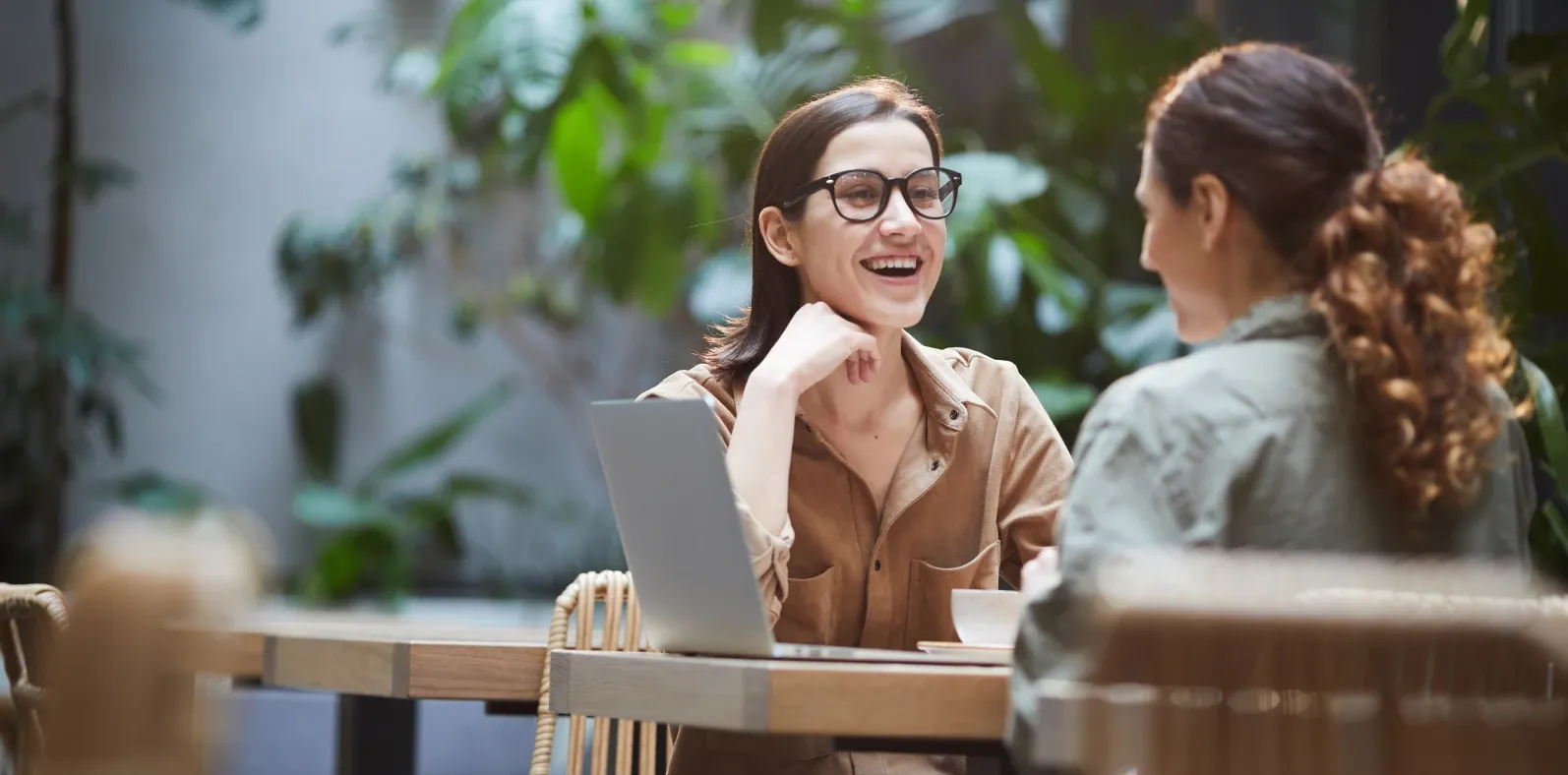 Two people laughing together over coffee at a café table