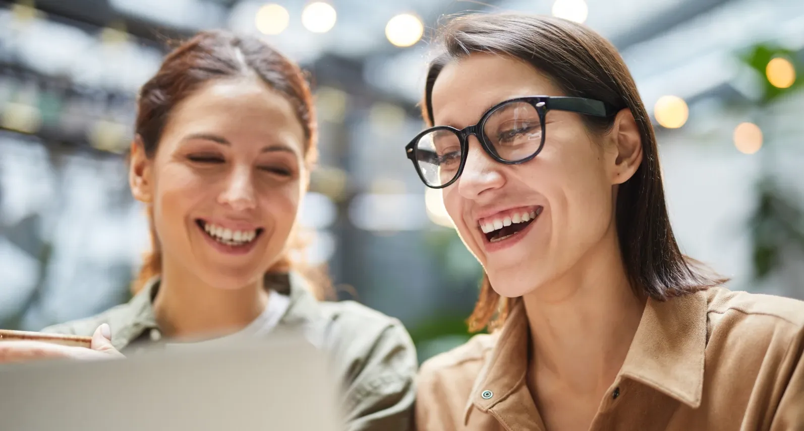 Two people laughing as they look at a laptop screen together