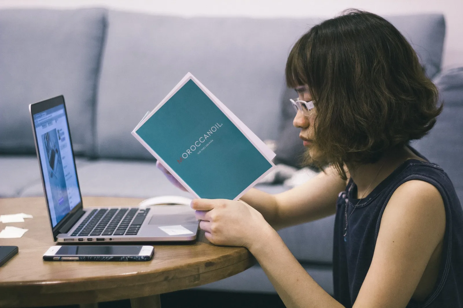 ノートパソコンの前でノートを読む女性